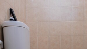 A toilet with a red towel on the seat, a water heater, and beige tiled walls.