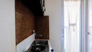 A compact kitchen with a gas stove, sink, and tiled backsplash.
