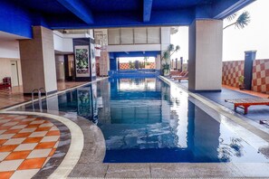 Una piscina con un piso de patrón a cuadros, pared de azulejos y vista al exterior.