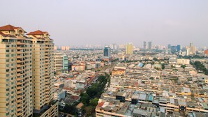 Un edificio alto con múltiples balcones y un denso paisaje urbano de fondo.