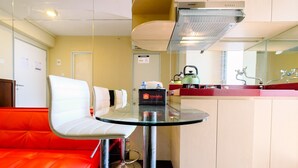 Ein modernes Hotelzimmer mit Glastisch, rotem Sofa und einer Küchenzeile.