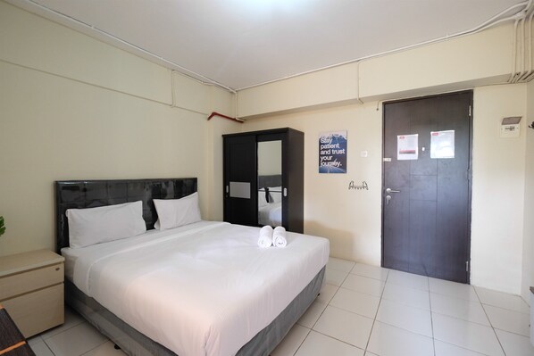 A hotel room with a bed, a nightstand, a wardrobe, and a door.