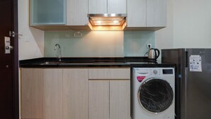 Una cucina compatta con mobili in legno, una lavatrice in acciaio inox e un forno incassato.