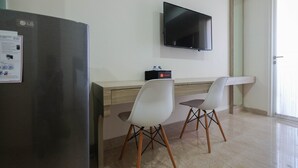 Una cucina moderna con frigorifero, televisore a schermo piatto montato a parete e due sedie bianche a gambe di legno.