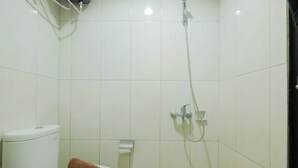 Ein kleines Badezimmer mit Toilette, Handtuch, Dusche und Toilettenpapierhalter.