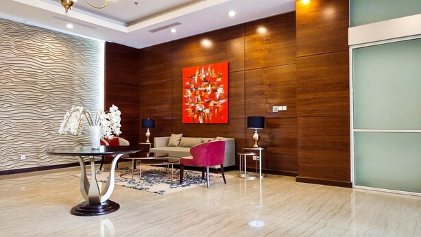 Eine moderne Lobby mit einer Holzwand, einem großen abstrakten Gemälde, einem Sofa, einem rosa Sessel und einem Tisch mit Blumen.