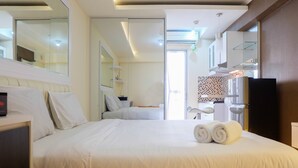 Habitación de hotel con una cama grande, un baño a la vista mediante una puerta abierta, un televisor y un minibar.