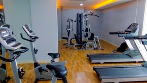 Un gimnasio con cintas de correr, elípticas y equipo de pesas.