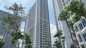 Un edificio moderno y alto con varios pisos y balcones, rodeado de árboles.