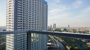 Un edificio alto con una fachada de ventanas en forma de cuadrícula, un río y un paisaje urbano al fondo.