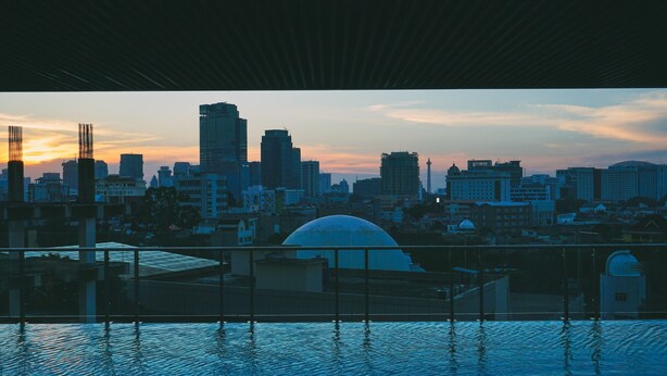 A city skyline at dusk with modern buildings and a dome structure in the foreground. - Comfortable and Modern 2BR Menteng Park Apartment (Jakarta)