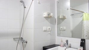 A bathroom with a white sink, a mirror, a shower with a handheld showerhead, and a towel rack. - Comfortable Studio at Beverly Dago Apartment near ITB (Bandung)