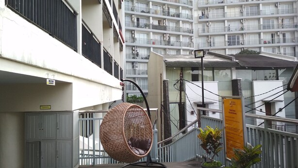 A balcony with a wicker chair, a potted plant, and a sign indicating a view of the sea. - Comfortable Studio at Beverly Dago Apartment near ITB (Bandung)