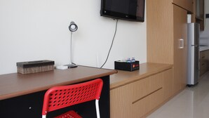 A kitchenette with a microwave, refrigerator, and a flat-screen TV mounted on the wall. - Comfortable Studio at Beverly Dago Apartment near ITB (Bandung)