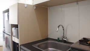 A compact kitchen with a stainless steel sink, a built-in oven, and a microwave. - Homey Studio Gateway Pasteur Apartment near Exit Toll (Cimahi)