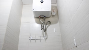 A white tiled bathroom with a wall-mounted toilet, a hand dryer, and a towel rack. - Homey Studio Gateway Pasteur Apartment near Exit Toll (Cimahi)
