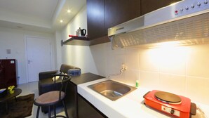 A compact kitchen with a stainless steel sink, a red appliance, and a chair. - Clean and Cozy 2BR Apartment @ Parahyangan Residence (Bandung)