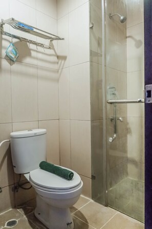Een badkamer met een toilet, een douchecabine van glas en een handdoekrek met een tas.