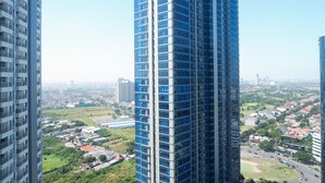Un immeuble de grande hauteur doté d’une façade moderne en verre, entouré d’un paysage urbain et de verdure.