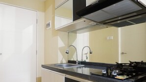 Une cuisine de taille réduite, équipée d’une cuisinière à gaz, de deux robinets et d’un évier.