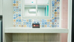 A bathroom with a tiled wall, a mirror, and two wooden stools. - Modern Living 1BR @Atlanta Residences Apartment With City View (Depok)