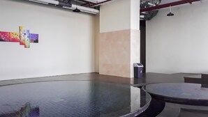 A conference room with a glass table, a trash bin, and a wall with colorful artwork. - Modern Living 1BR @Atlanta Residences Apartment With City View (Depok)