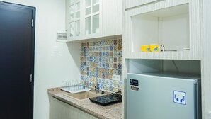 A kitchen with a sink, countertop, and a refrigerator. - Modern Living 1BR @Atlanta Residences Apartment With City View (Depok)