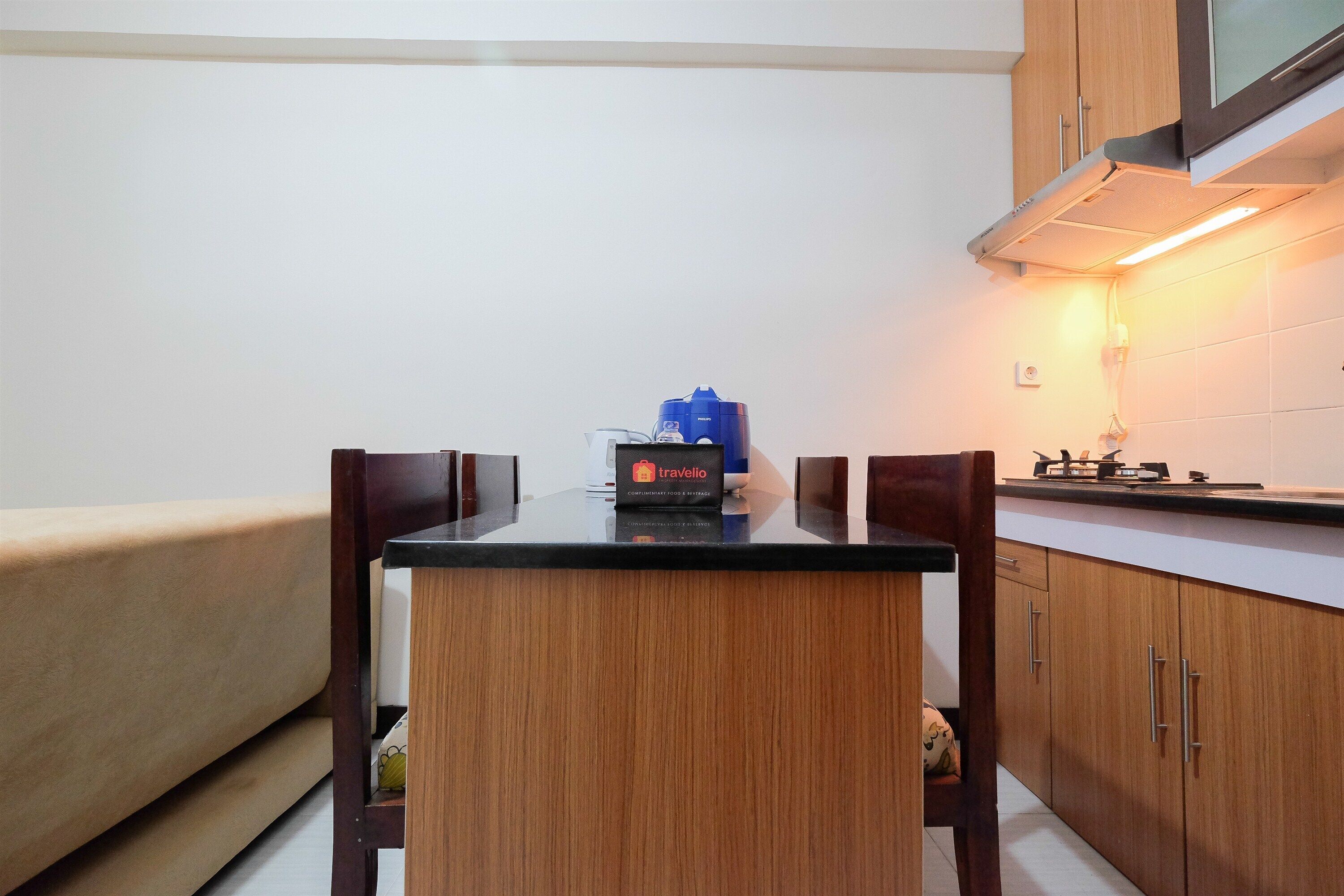 Una cocina compacta con una mesa de comedor, armarios de madera y un microondas.