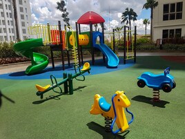A playground with a slide, swings, and a seesaw.
