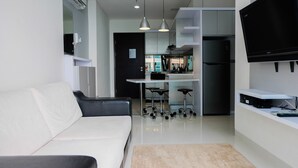 A modern living room with a white sofa, a coffee table, and a flat-screen TV mounted on the wall. - Stylish 2BR at Brooklyn Apartment near Alam Sutera (South Tangerang)
