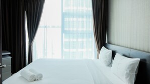 A hotel room with a large bed, two pillows, a nightstand, and a window with curtains. - Stylish 2BR at Brooklyn Apartment near Alam Sutera (South Tangerang)