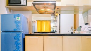 A kitchen with a blue refrigerator, a microwave above it, and a stove. - Highest Value 2BR at Great Western Apartment (Tangerang)