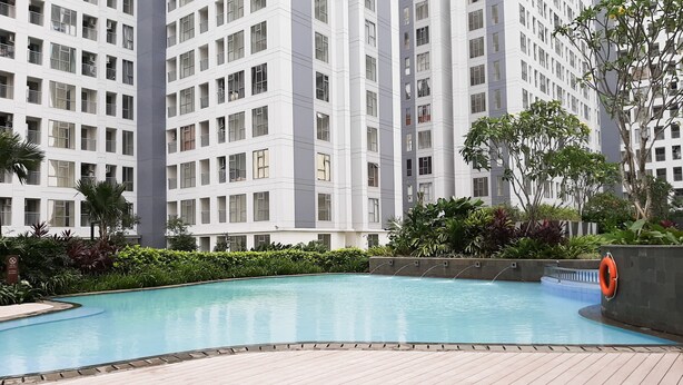 Un edificio residencial moderno con piscina rodeada de vegetación.