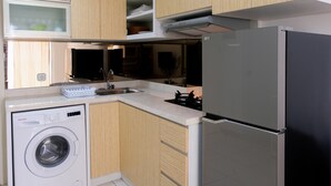 Una cocina compacta con lavadora, refrigerador y armarios de madera.