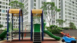 Un patio de recreo con tobogán, estructura para escalar y columpios.