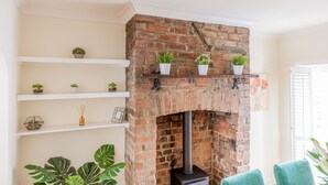 A brick fireplace with shelves above holding potted plants and a framed picture. - Strayside Cottage Harrogate. Dog friendly. 5 min walk hospital. 15 min walk town (Harrogate)