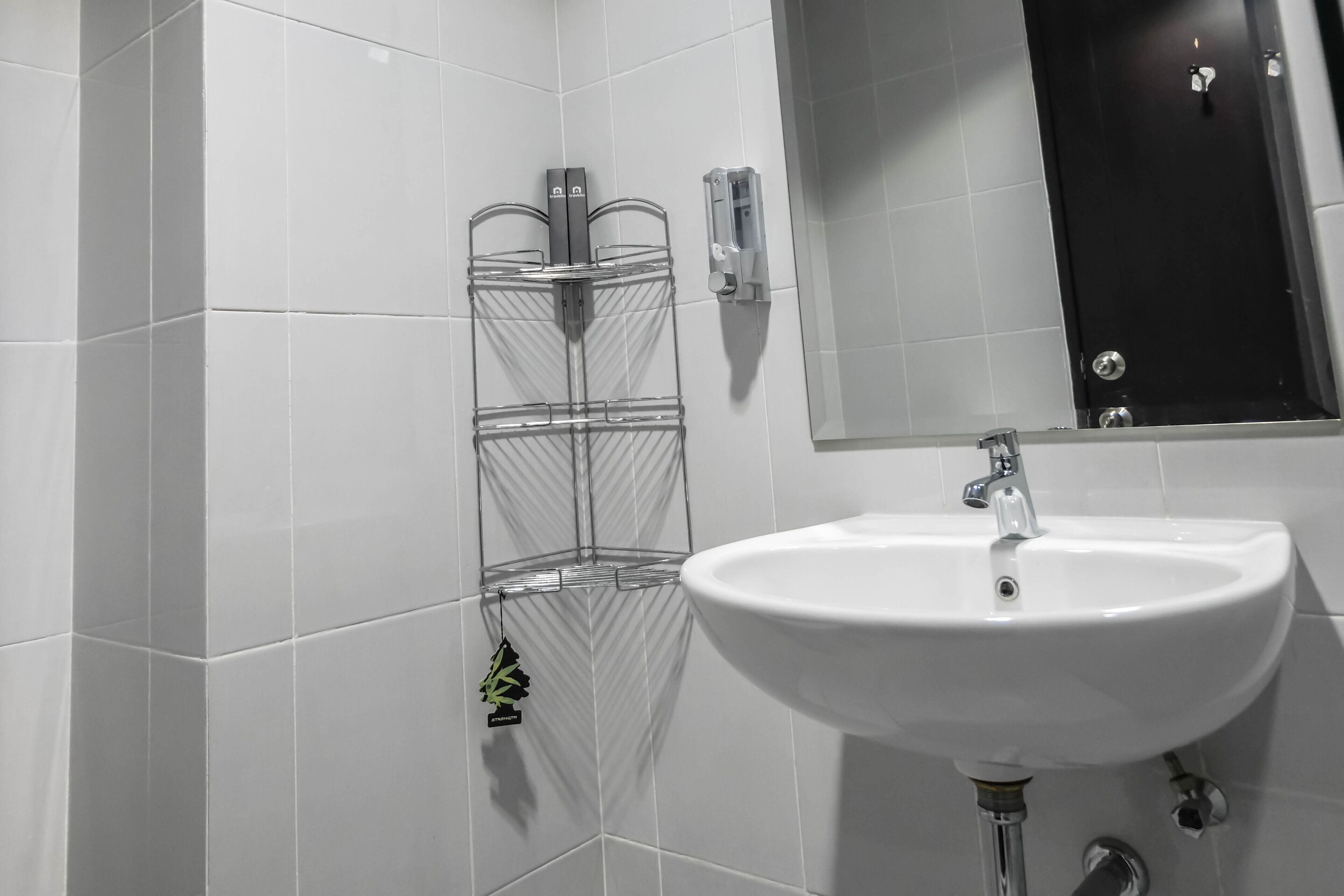 Un baño con un lavamanos blanco, un espejo y un perchero para toallas.