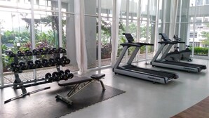 A gym with treadmills, dumbbells, and a bench.