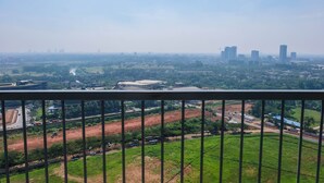 A cityscape with a mix of greenery and urban development, viewed from a balcony.