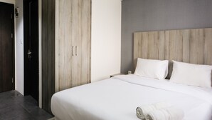 A hotel room with a large bed, wooden wardrobe, and a grey accent wall.