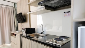 A modern kitchen with a flat-screen TV, a sink, a stove, and a microwave.