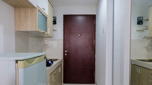 Una cocina estrecha con puerta de madera, armarios blancos y lavavajillas.