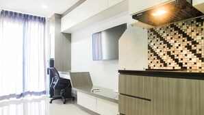 A modern kitchen with a tiled backsplash, a built-in stove, and a sleek countertop. - 1BR with Working Space The Oasis Apartment Cikarang (Cikarang)