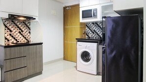 A compact kitchen with a washing machine, a microwave, and a refrigerator. - 1BR with Working Space The Oasis Apartment Cikarang (Cikarang)
