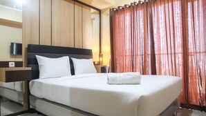 A neatly made bed with white linens, a wooden headboard, and a nightstand with a lamp. - Spacious 1 BR at The Oasis Cikarang Apartment (Cikarang)
