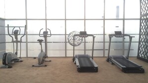 A gym with four treadmills, two stationary bikes, and one elliptical machine. - Spacious 1 BR at The Oasis Cikarang Apartment (Cikarang)