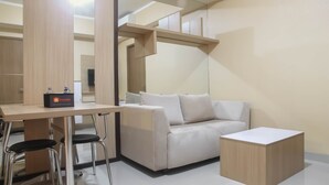 A modern, minimalist room with a sofa, a small table, and two chairs. - Spacious 1 BR at The Oasis Cikarang Apartment (Cikarang)