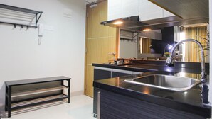 A modern kitchen with a black countertop, stainless steel sink, and wooden cabinets.