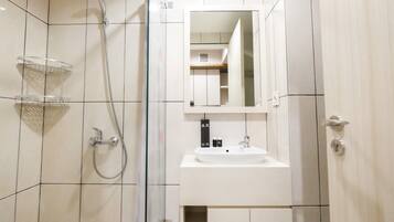 Un baño moderno con ducha, lavamanos y armarios para guardar objetos.
