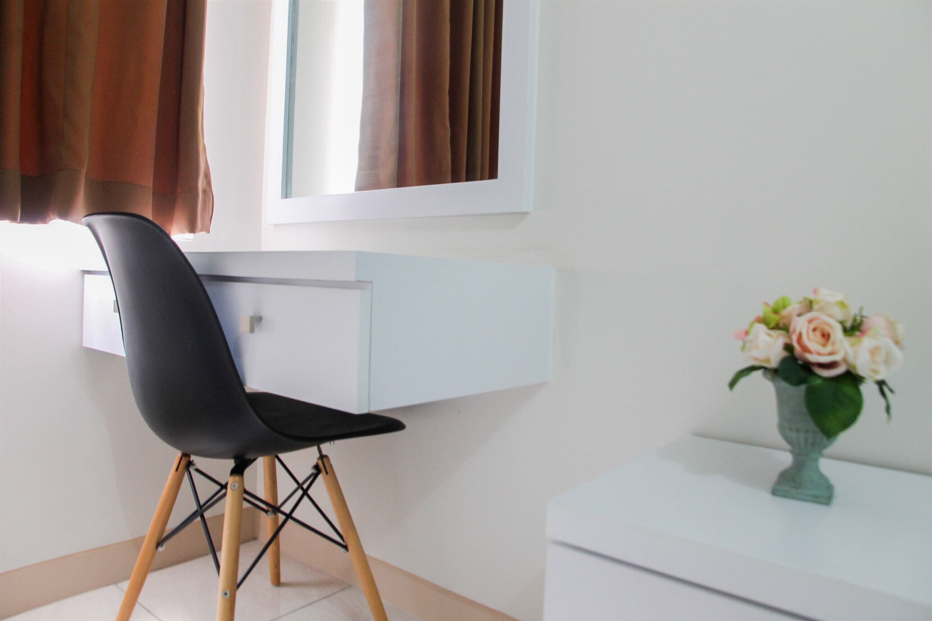A modern room with a desk, chair, and a vase of flowers.